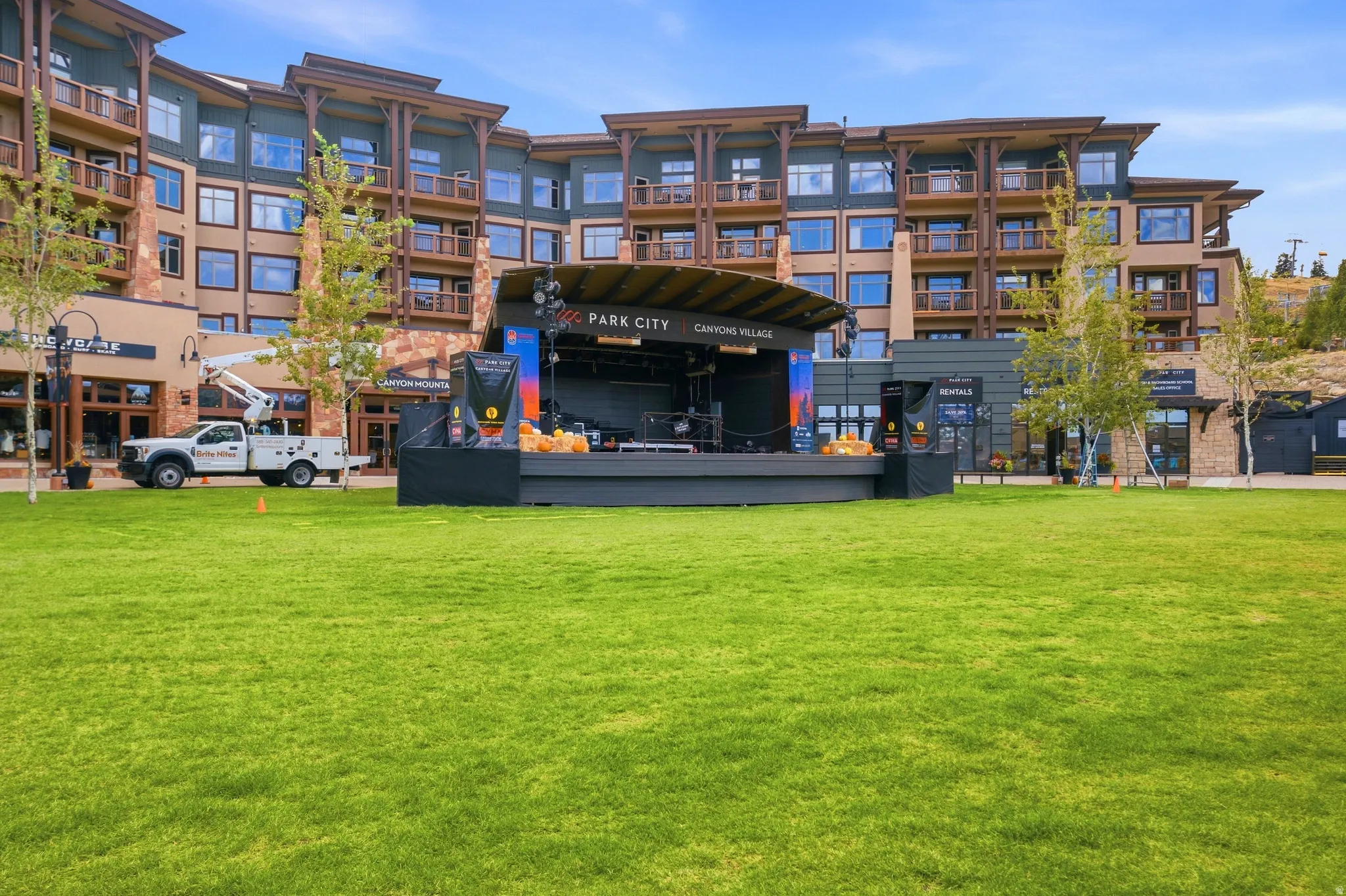 Manicured green lawn with a large, multi-story building featuring balconies and stone accents