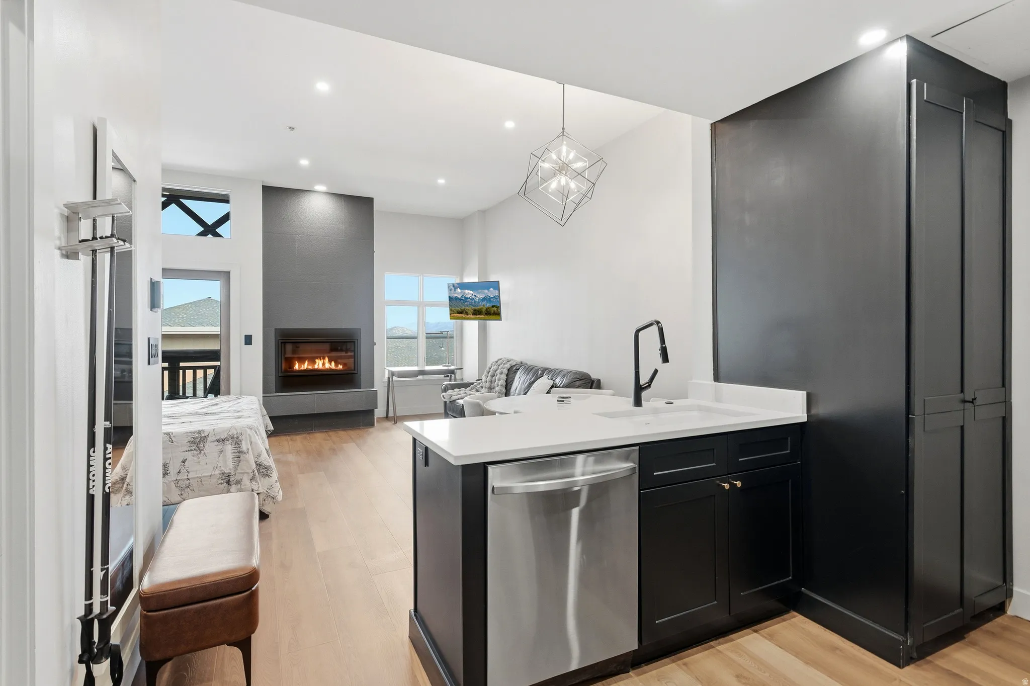 Open-concept living area featuring a modern fireplace, wood-finish flooring, and a kitchen island with a built-in dishwasher