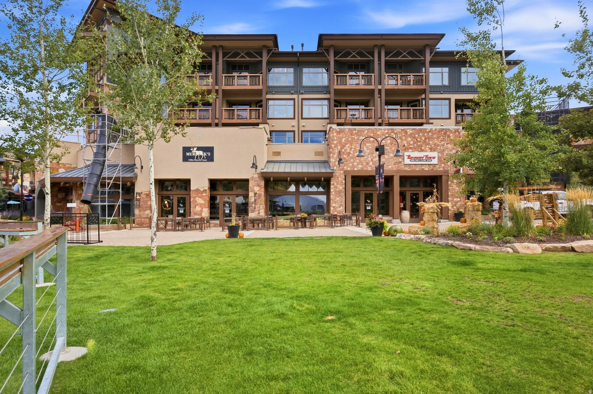 Multi-story building with stone and stucco facade, multiple balconies with wood railings, and ground-level commercial spaces