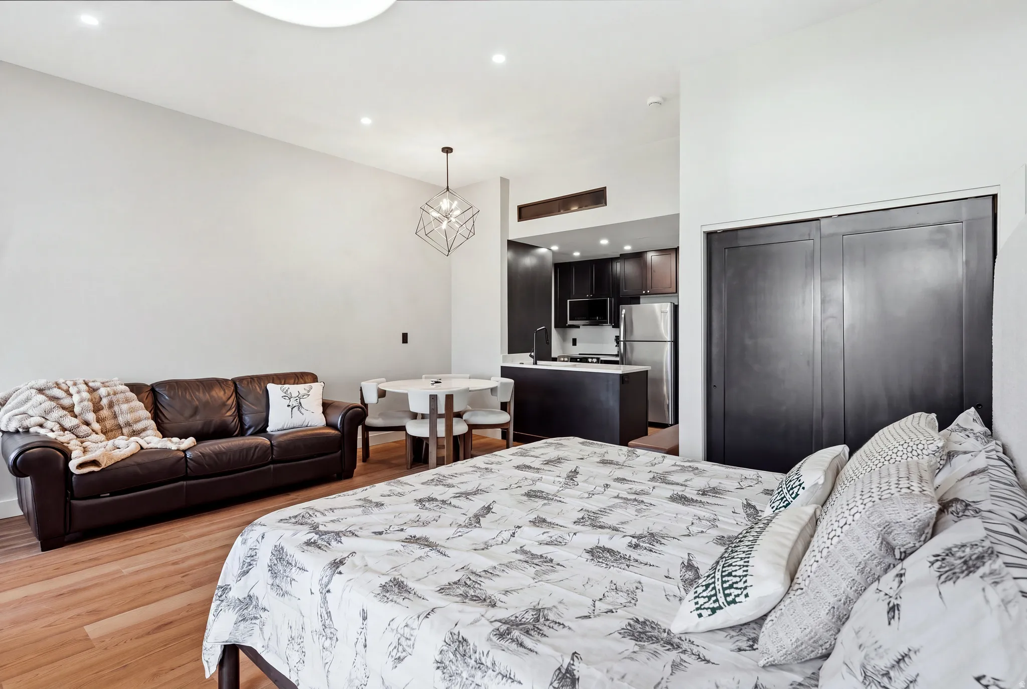 Open-concept living space with wood-finish flooring, recessed lighting, and a modern geometric pendant light