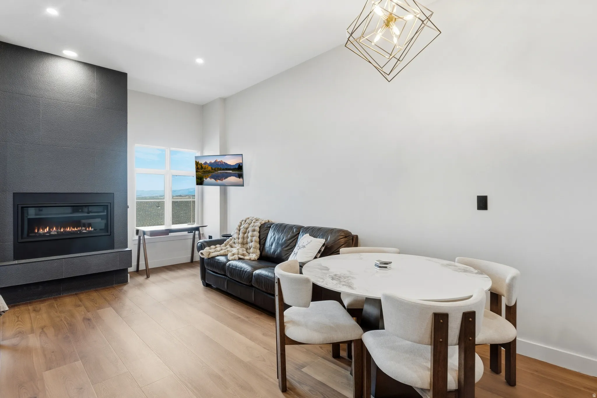 Gas fireplace with a dark tile surround, light wood-finish flooring, and recessed ceiling lights