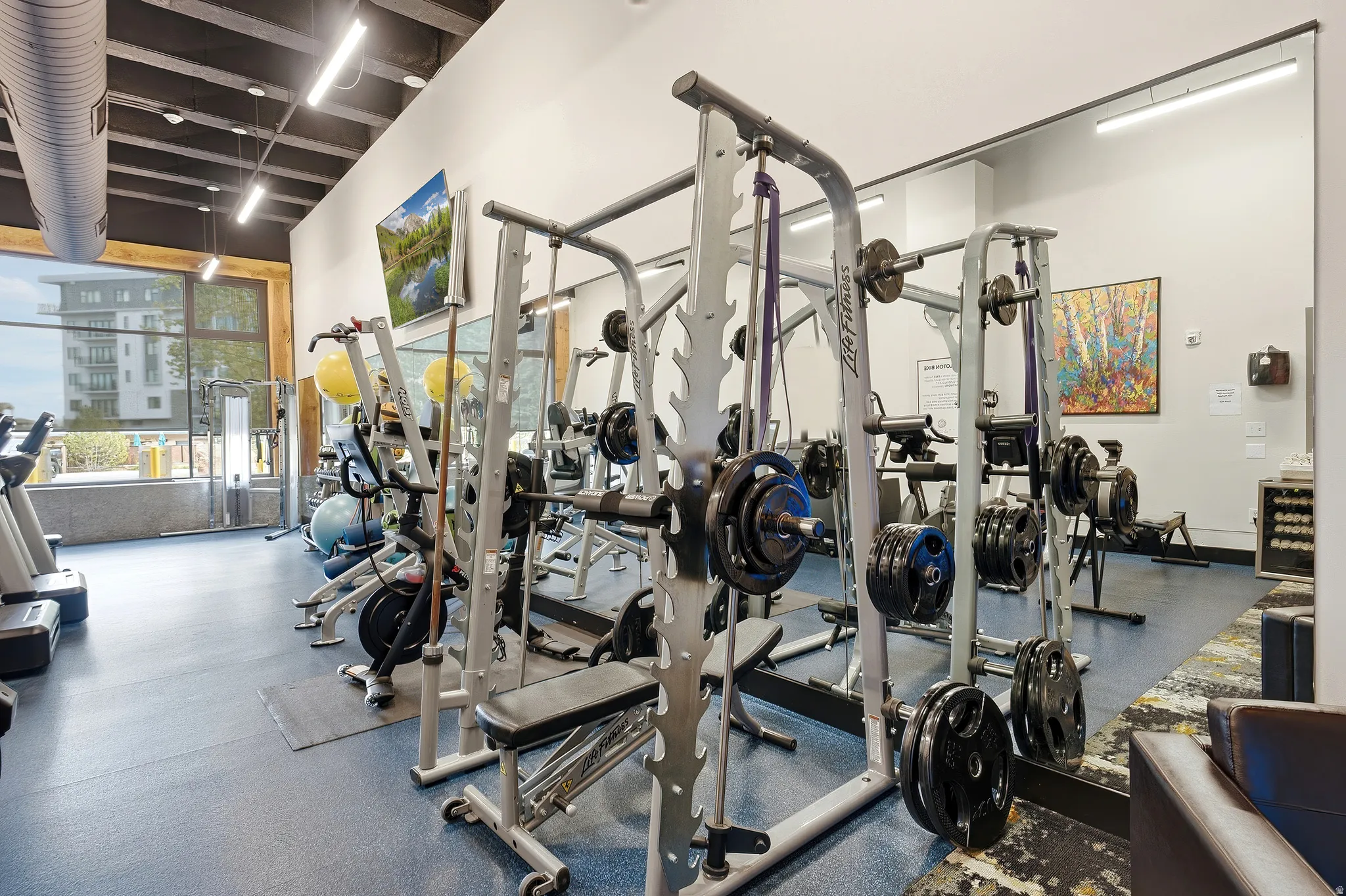 Fitness center with rubberized flooring, exposed ceiling beams, and integrated lighting