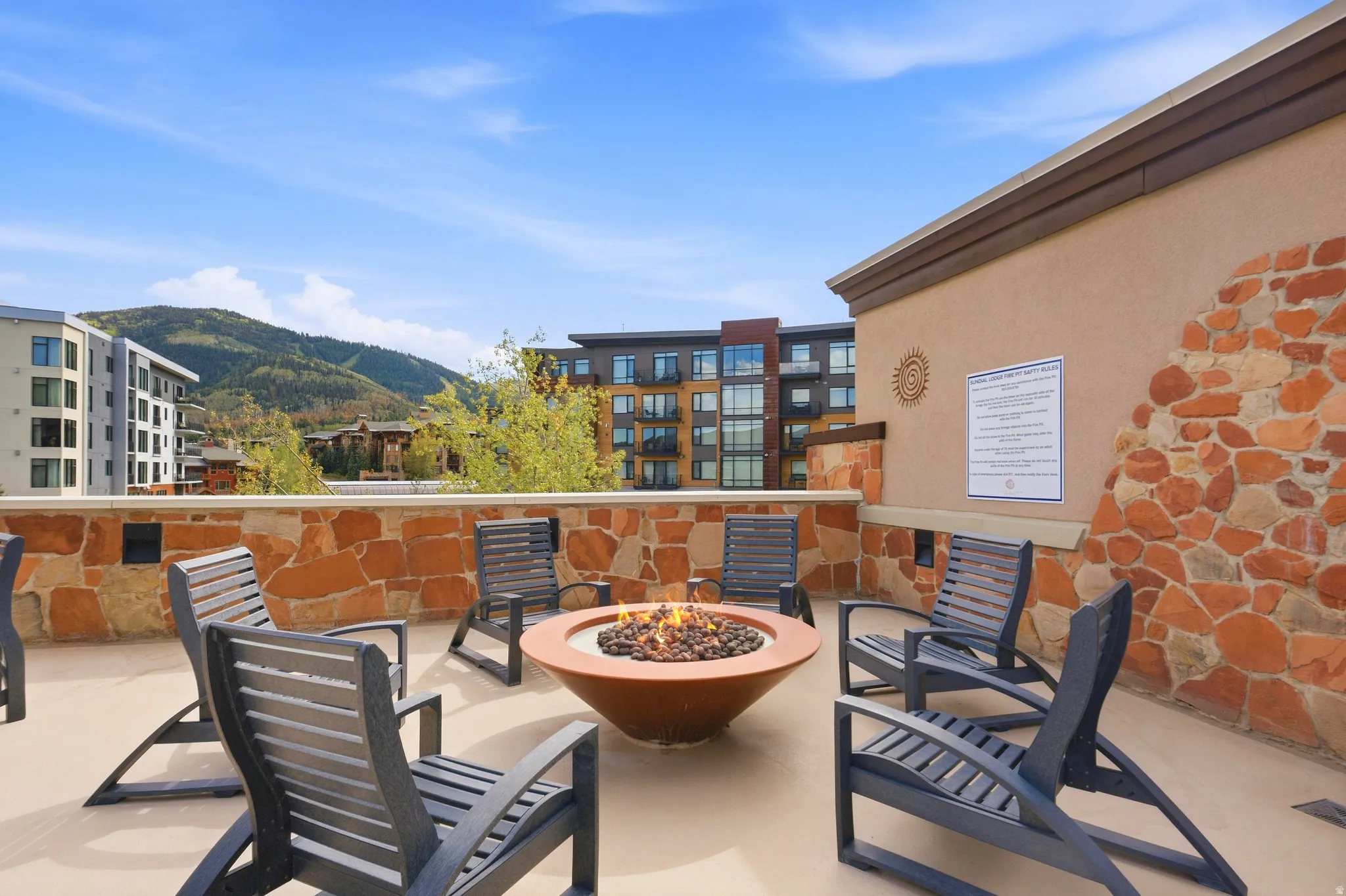 Rooftop patio with a built-in fire pit, stone accent wall, and expansive mountain scenery