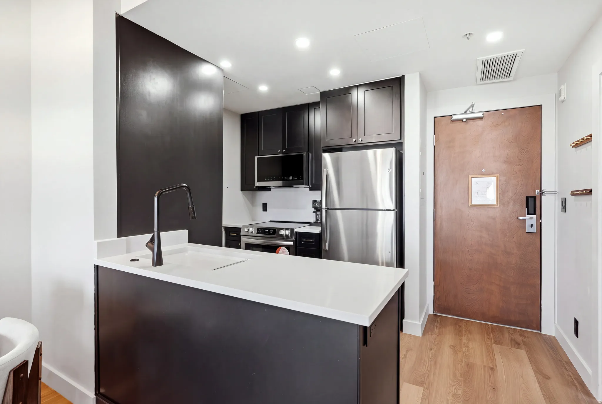 Modern kitchen featuring black cabinetry, stainless steel appliances, and light-toned countertops