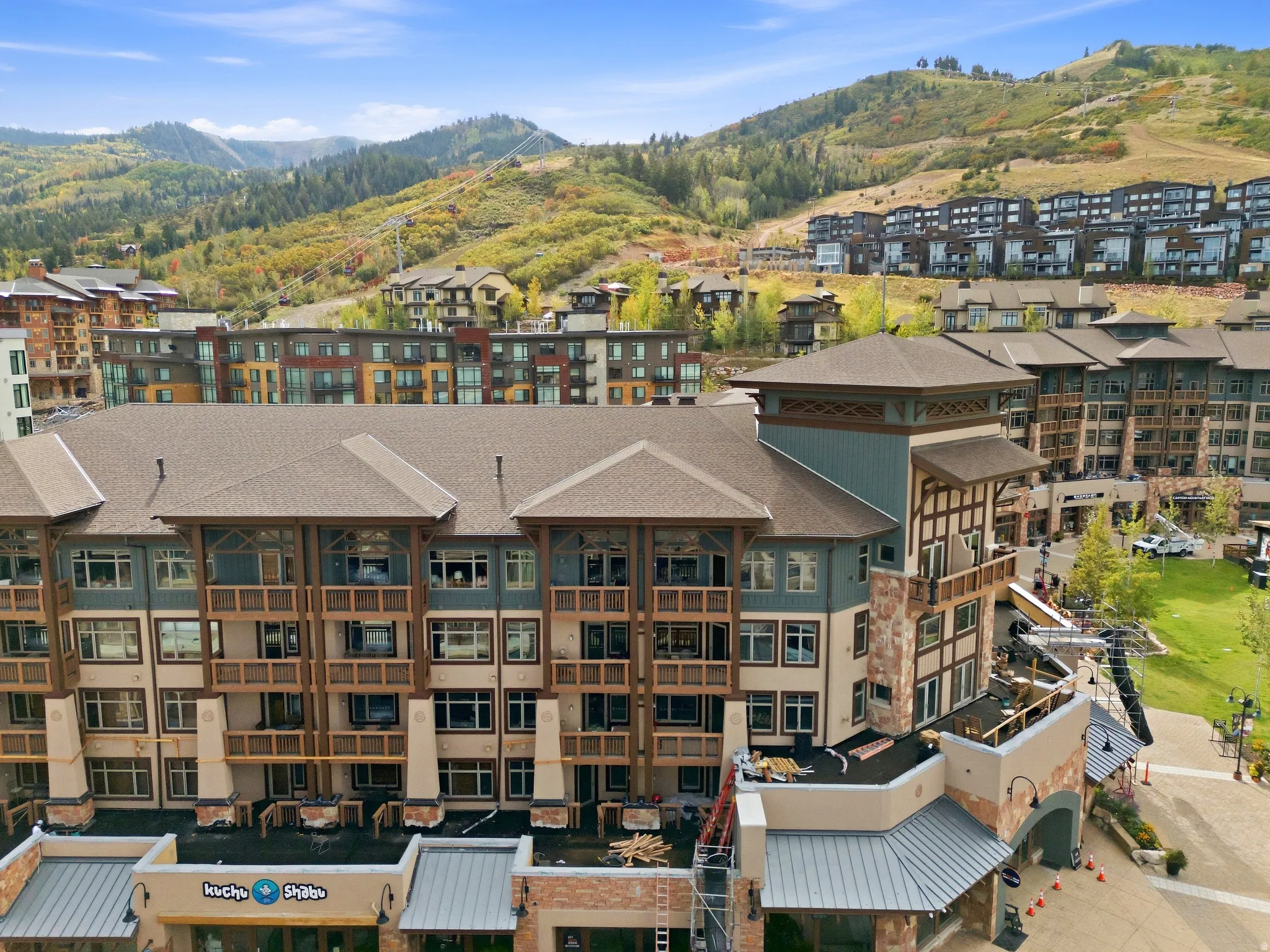 Multi-story building featuring integrated commercial spaces, multiple balconies, and visible mountain scenery