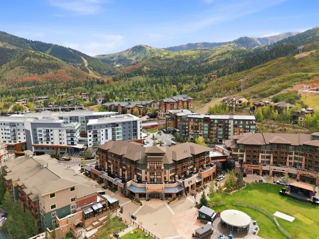 Mixed-use development featuring diverse architectural styles, integrated green spaces, and a mountainous backdrop