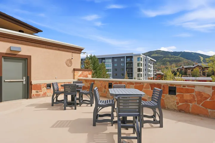 Outdoor patio space with stone veneer wall, stucco exterior, and mountain backdrop