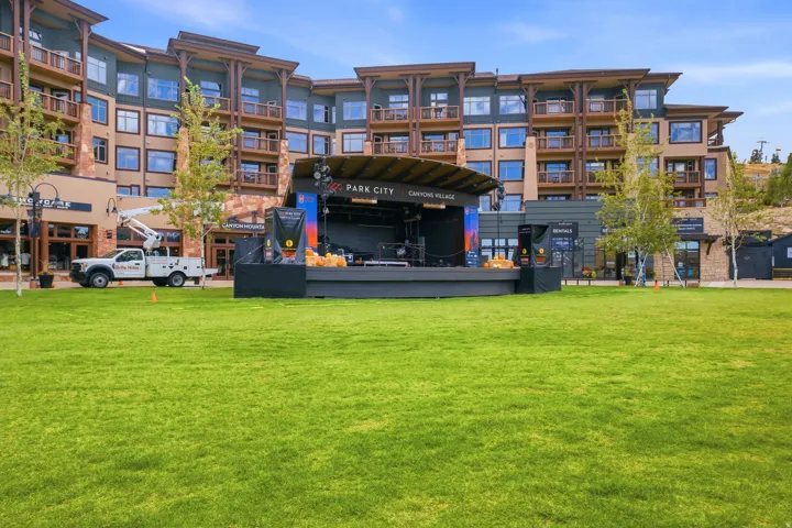 Manicured green lawn with a large, multi-story building featuring balconies and stone accents
