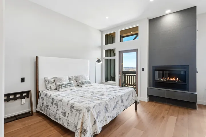 Hardwood flooring, contemporary fireplace with tiled surround, high ceilings, large windows, and a glass-paneled door