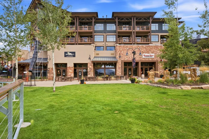 Multi-story building with stone and stucco facade, multiple balconies with wood railings, and ground-level commercial spaces