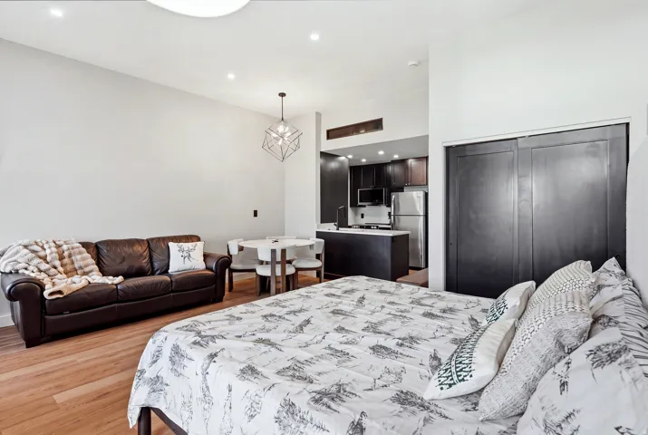 Open-concept living space with wood-finish flooring, recessed lighting, and a modern geometric pendant light