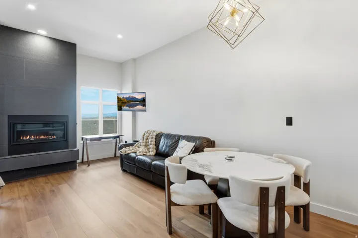 Gas fireplace with a dark tile surround, light wood-finish flooring, and recessed ceiling lights