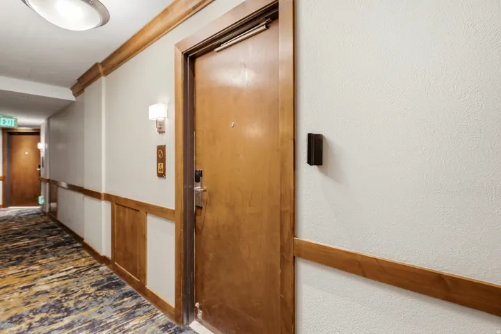 Corridor featuring wood-panel wainscoting, textured walls, and a patterned carpet