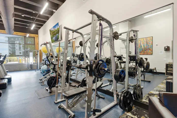 Fitness center with rubberized flooring, exposed ceiling beams, and integrated lighting
