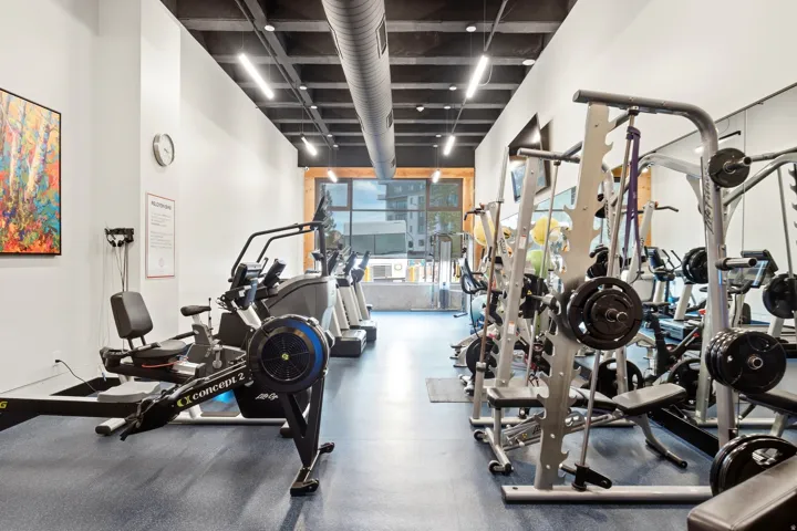 Fitness center with exposed ductwork, large windows, and track lighting