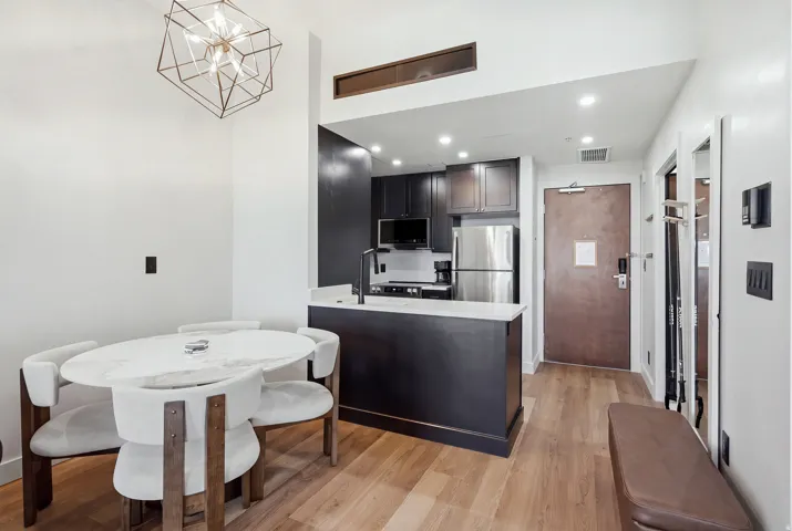 Modern open-concept living area with wood-finish flooring, a contemporary geometric chandelier, and recessed lighting
