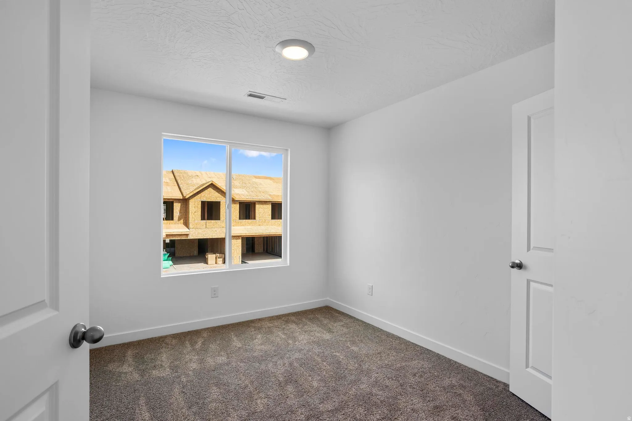 Recessed ceiling light, neutral wall paint, carpeted flooring, and a single window