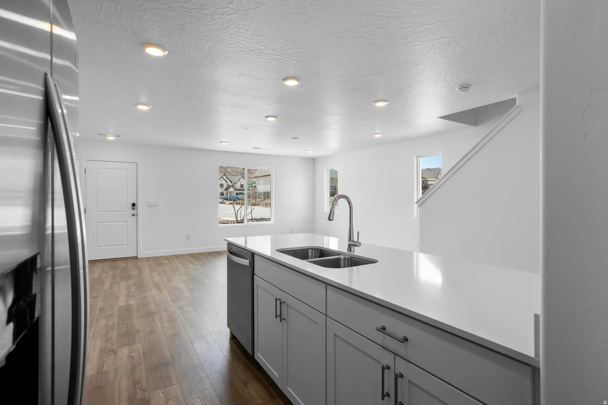 Kitchen island with a double basin sink, stainless steel faucet, and light-toned countertops