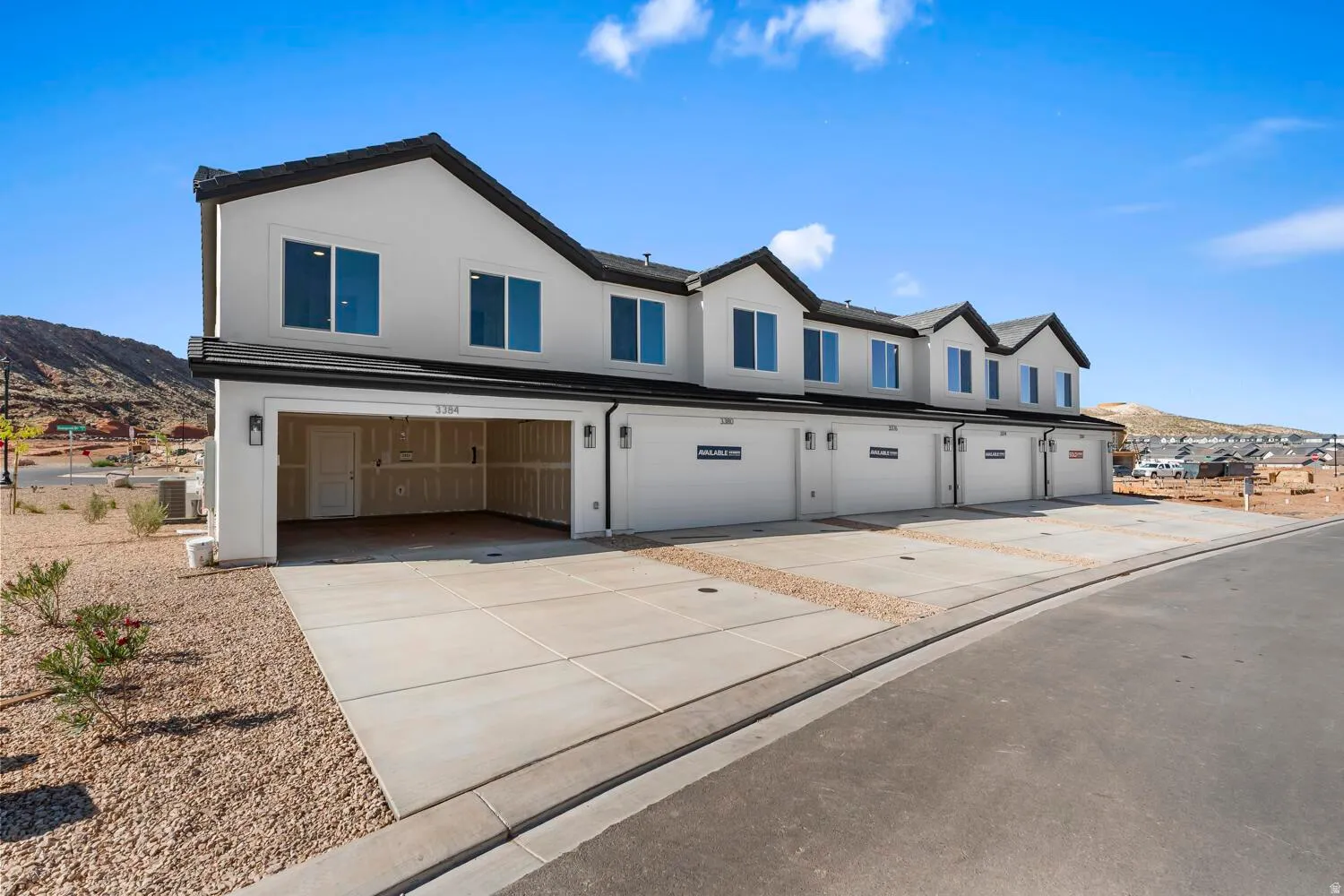 Multi-unit property with a white stucco exterior, black trim, and gabled roofs