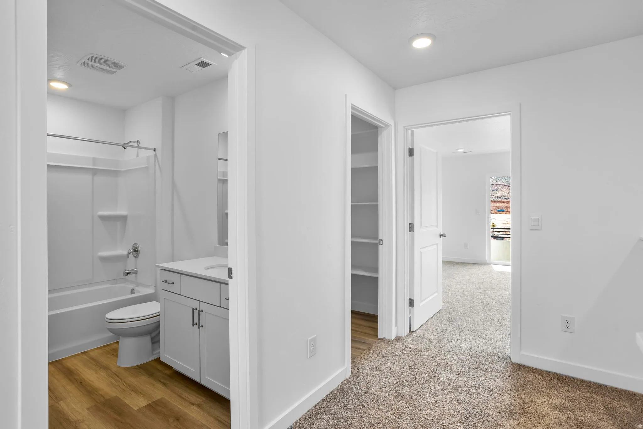 Bathroom featuring wood-finish flooring, a white vanity with a rectangular sink, and a combination tub/shower
