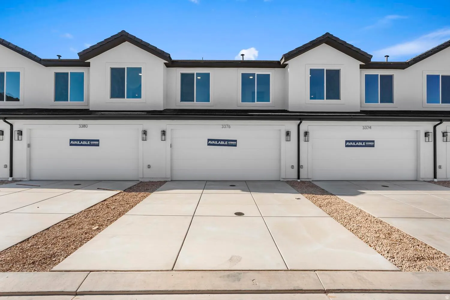 Contemporary exterior facade featuring multiple large windows, attached garages with panel doors, and exterior wall-mounted lighting