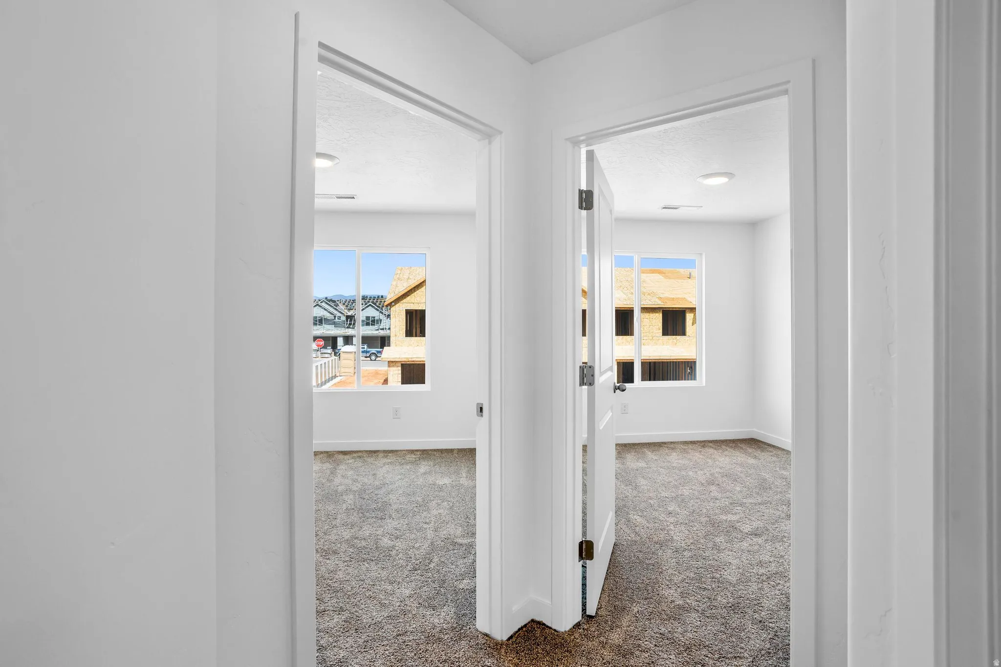 Two rooms featuring neutral-toned carpet, white walls, and recessed lighting