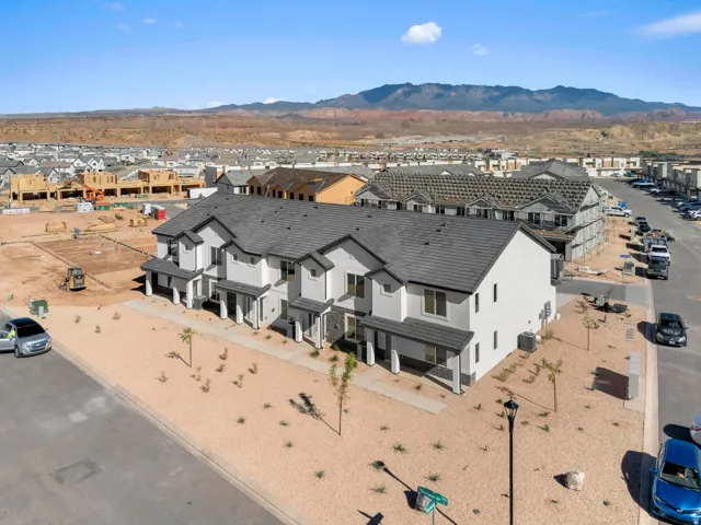 Multi-story townhome with a dark gray roof, white exterior siding, and dark trim accents