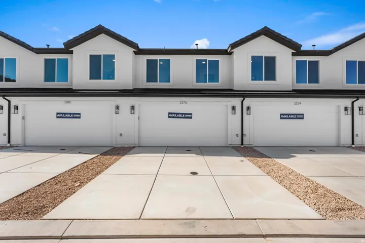 Contemporary exterior facade featuring multiple large windows, attached garages with panel doors, and exterior wall-mounted lighting