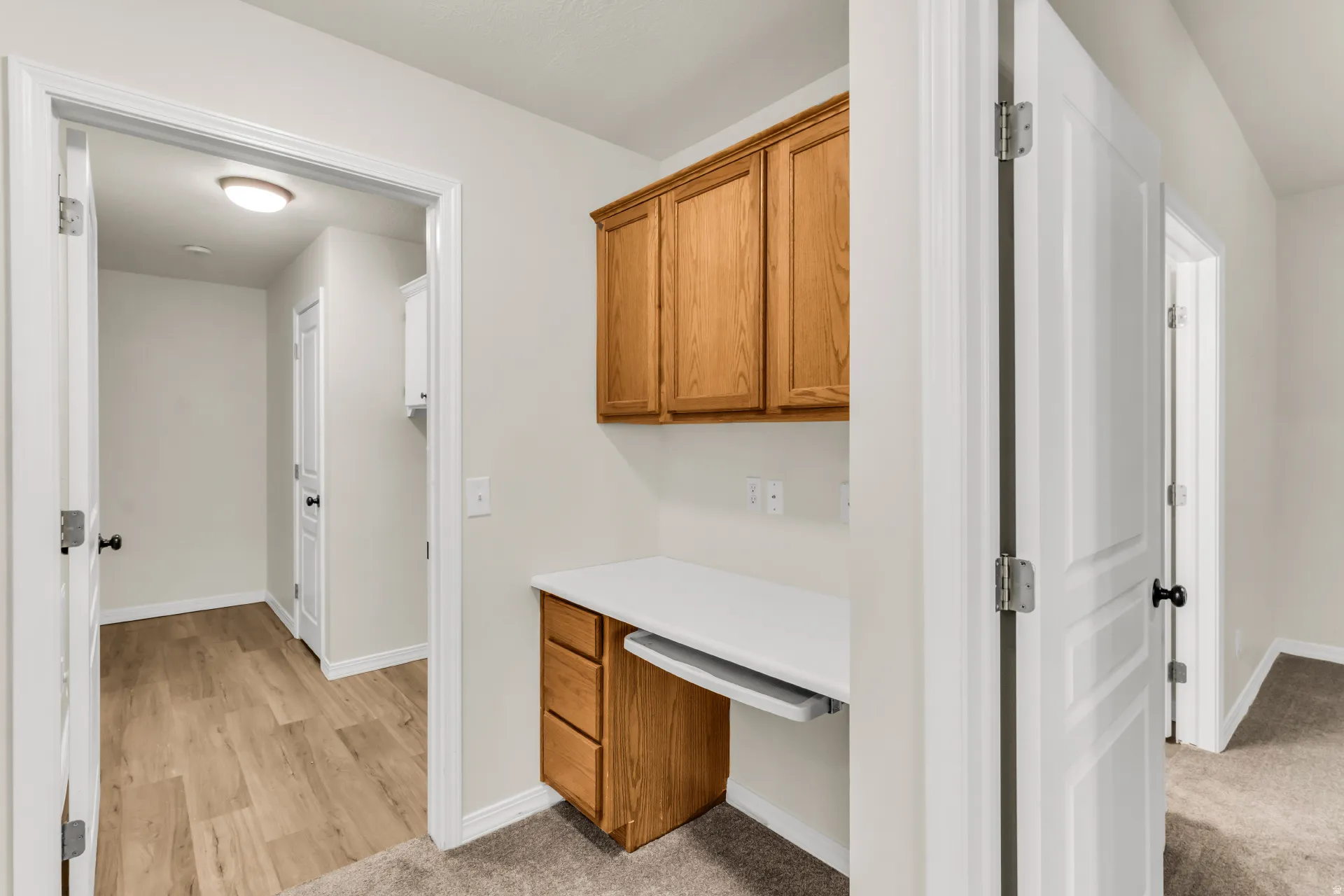Built-in desk with wood-finish cabinetry, white countertop, and integrated keyboard tray.