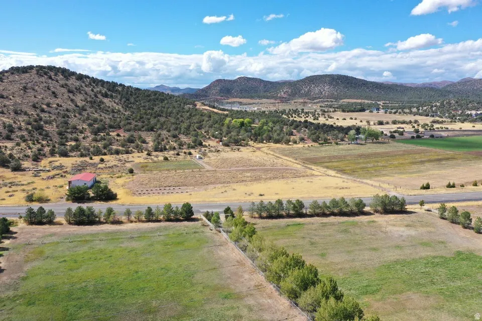 Expansive rural landscape featuring a red-roofed structure, cultivated fields, and distant mountainous terrain