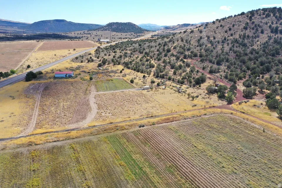 Expansive acreage featuring cultivated fields, a distinct red-roofed structure, and a winding unpaved road