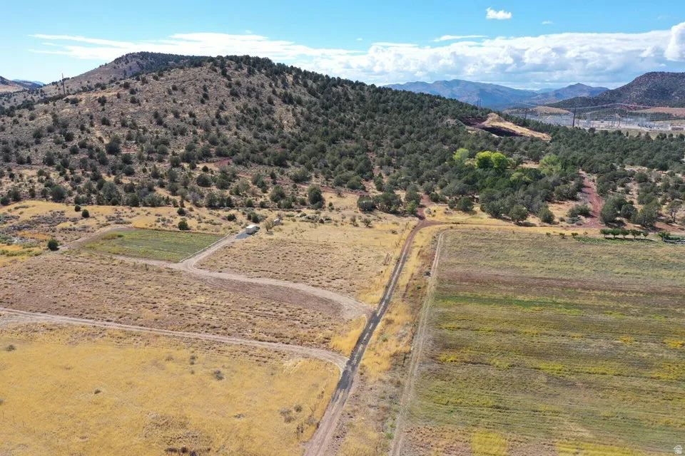 Expansive land featuring a vegetated hillside, cultivated fields, and a clear sky backdrop