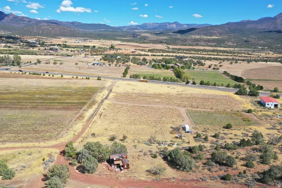 Mountain scenery with expansive land, a distinct red-roofed barn, and a residential structure