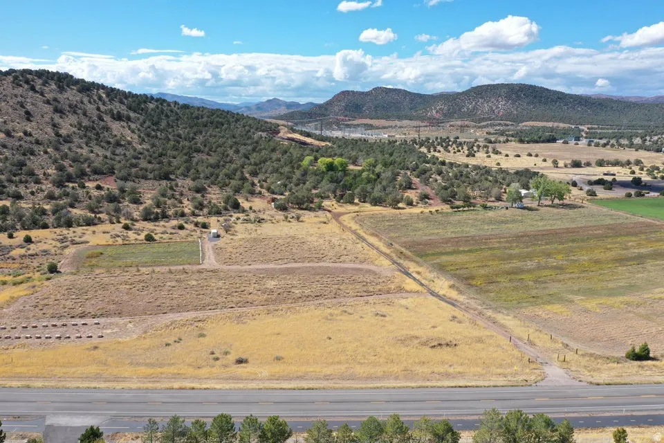 Expansive rural property featuring an unpaved road, varied terrain with cultivated and natural areas, and distant mountainous scenery