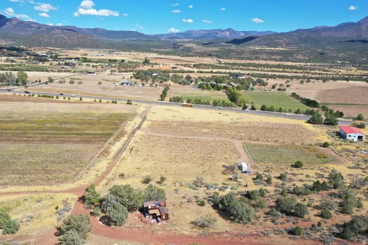 Mountain scenery with expansive land, a distinct red-roofed barn, and a residential structure
