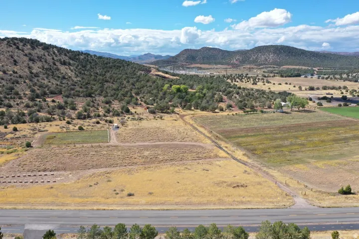 Expansive rural property featuring an unpaved road, varied terrain with cultivated and natural areas, and distant mountainous scenery