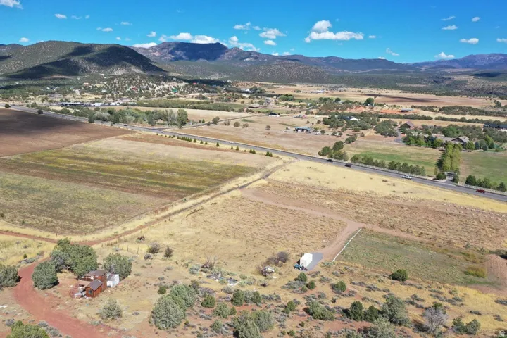 Expansive property featuring varied terrain, a distant paved road, and mountain scenery