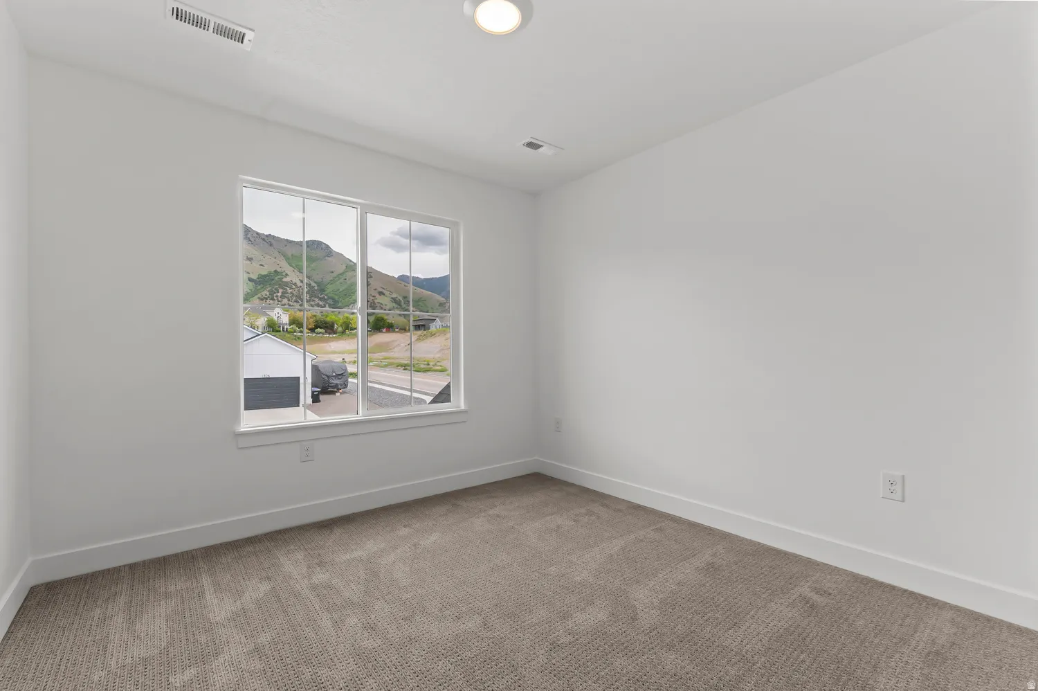 Neutral wall colors, carpet flooring, and a large window with mountain scenery