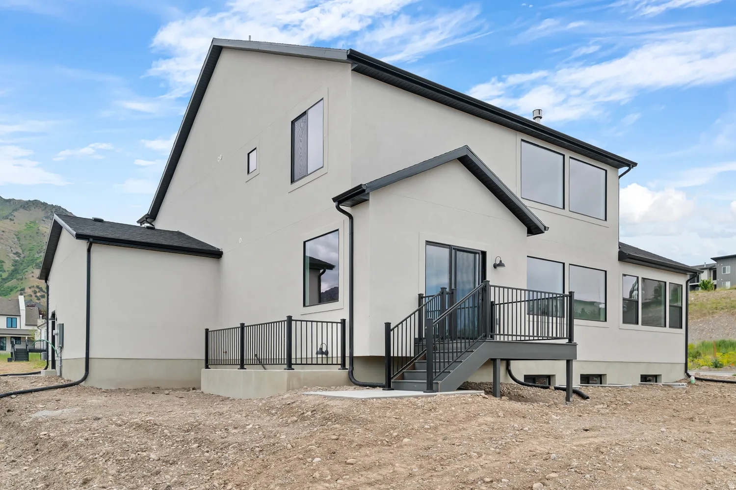 Contemporary exterior with light-colored siding, black-framed windows, a walk-out deck with dark railing, and a sloped roofline