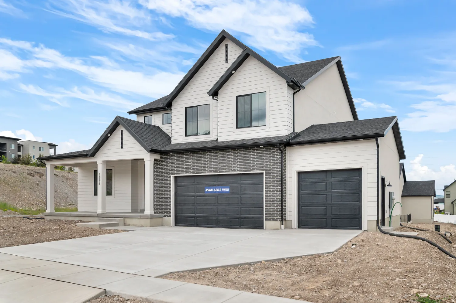 Contemporary exterior with a covered porch, horizontal siding, dark brick accents, and a two-car garage