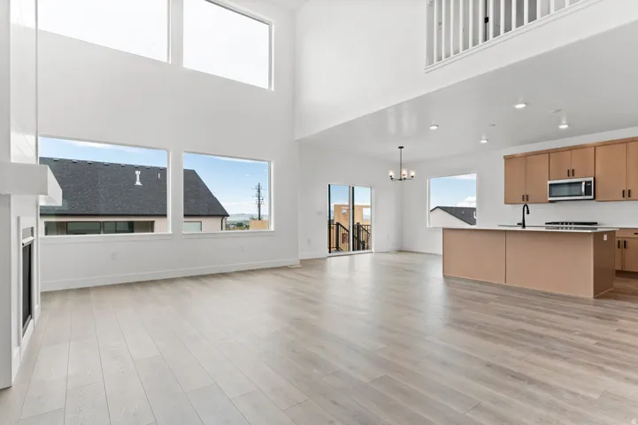 Two-story ceiling, large windows, wood-finish flooring, fireplace, and a kitchen island with built-in sink and stove
