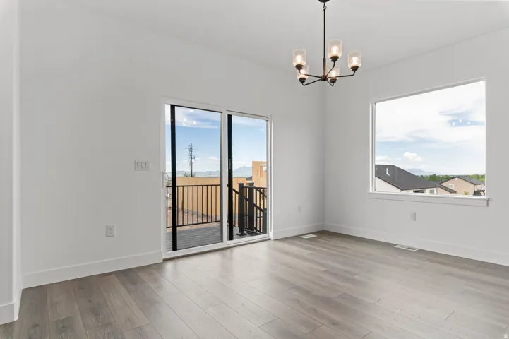Wood-finish flooring, white walls, modern chandelier, sliding glass door, and large window