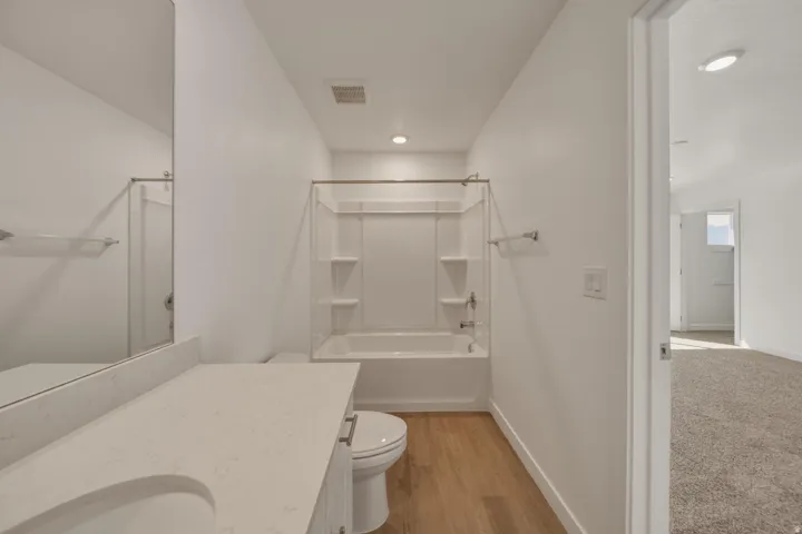 White vanity with a single basin sink and light-colored countertop