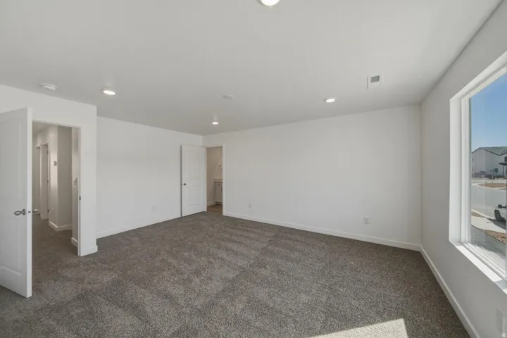 Spacious room featuring carpeting, recessed lighting, white walls, and a large window