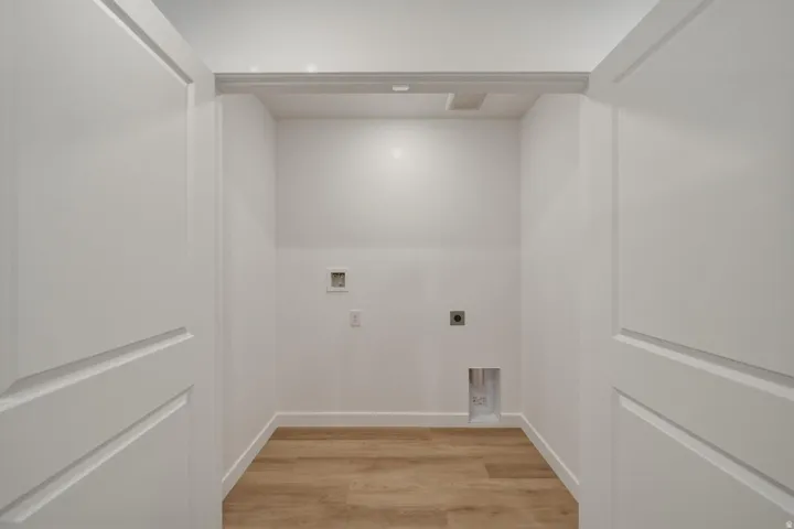 Dedicated laundry area with wood-finish flooring, white walls, and pre-installed utility connections
