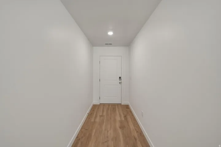 Entryway featuring wood-finish flooring, recessed lighting, and a paneled door with modern hardware