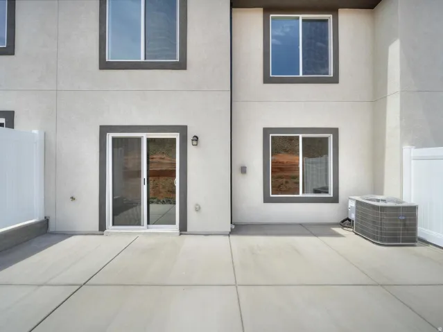 Concrete patio with white privacy fencing and a sliding glass door