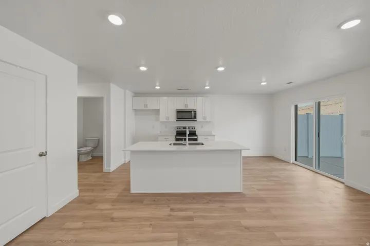 Modern kitchen featuring white cabinetry, a central island, stainless steel appliances, and wood-finish flooring