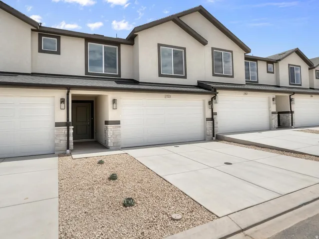 Stucco exterior with stone accents, integrated two-car garage, and a covered entry