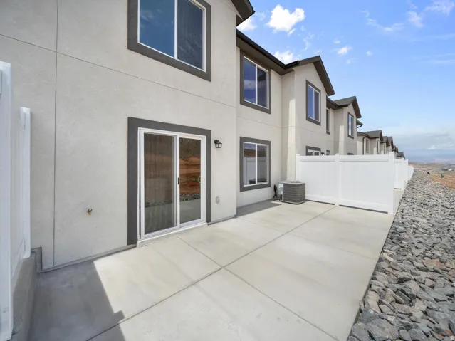 Private patio featuring a concrete surface, white privacy fencing, and exterior sliding glass doors